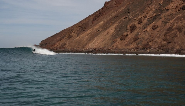 hombre surfeando al lado de una montana